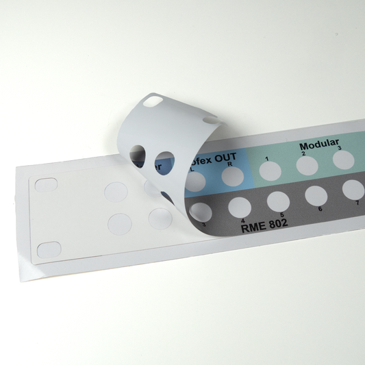 Patch bay label peeling from the backing sheet to show cut out holes.